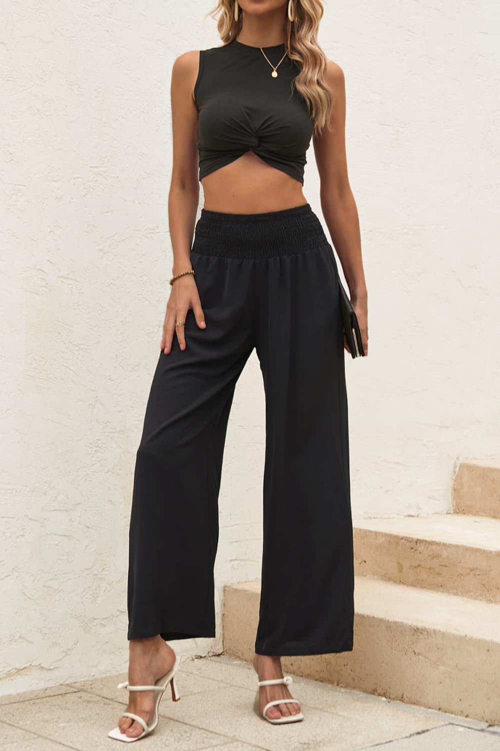 Front view of model wearing two piece crop top pants set in the color black